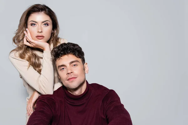 Casual jeune couple en col roulé sauteurs posant isolé sur gris — Photo de stock