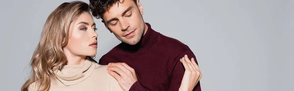 Casual joven pareja en jerséis cuello alto abrazando aislado en gris, bandera - foto de stock