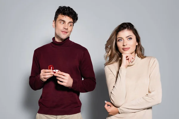 Casual jeune homme avec bague de fiançailles près de femme isolé sur gris — Photo de stock