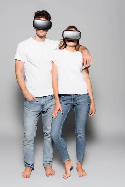 Случайная молодая пара в белых футболках и наушниках, изолированных на сером — стоковое фото