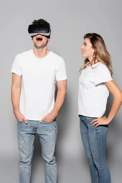 Shocked man in vr headset near woman isolated on grey — Stock Photo