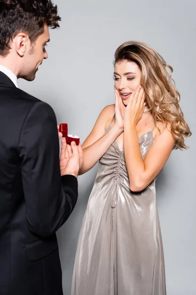Elegante joven haciendo propuesta de matrimonio aislado en gris - foto de stock