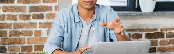 Teilansicht eines Afrikaners, der neben Laptop gestikuliert, Banner — Stockfoto