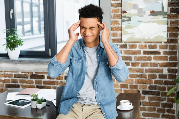 Hombre afroamericano con los ojos cerrados sufriendo de migraña - foto de stock