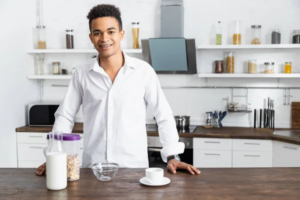 Щасливий афроамериканський чоловік стоїть біля столу зі сніданком — стокове фото