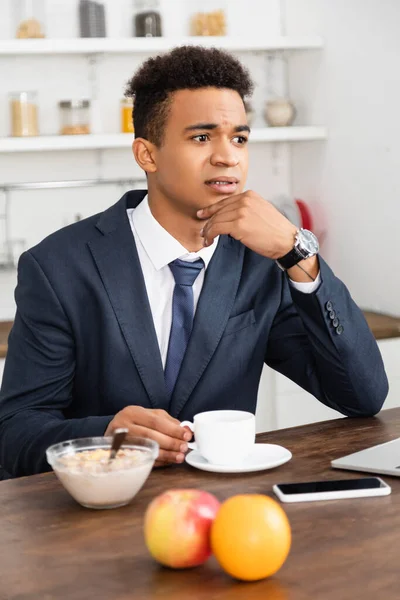 Preocupado empresário afro-americano tomando café da manhã e pensando em casa — Fotografia de Stock