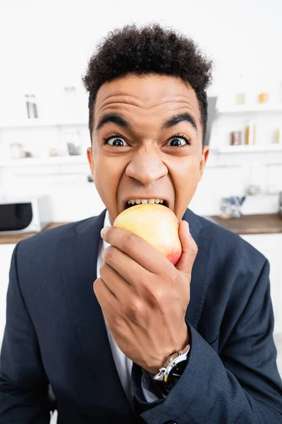 Rizado africano americano hombre de negocios comer manzana en casa - foto de stock