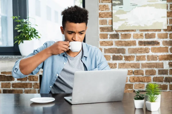 Afrikanisch-amerikanischer Mann trinkt Kaffee während er von zu Hause aus arbeitet — Stockfoto