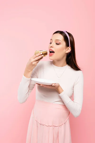 Giovane bella donna incinta mangiare torta isolato su rosa — Foto stock