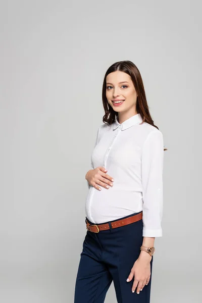 Sonriente joven embarazada mujer de negocios aislado en gris - foto de stock