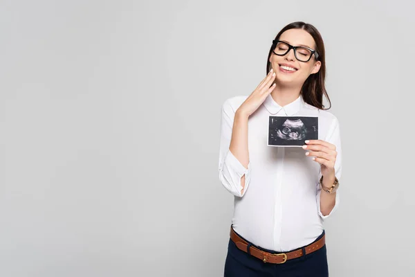 Усміхнена молода вагітна бізнес-леді в окулярах тримає ультразвукове сканування ізольовано на сірому — стокове фото