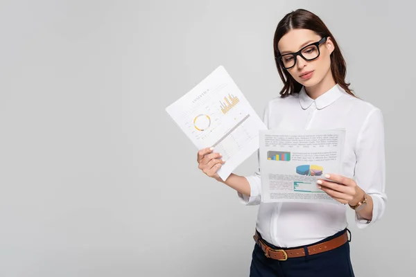 Young pregnant businesswoman in glasses holding papers isolated on grey — Stock Photo