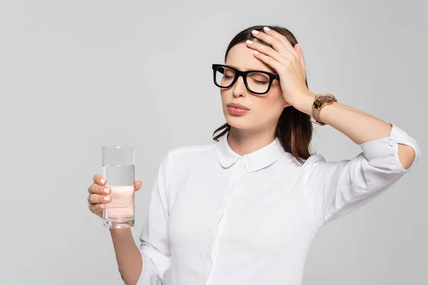 Fatigué jeune femme d'affaires enceinte dans des lunettes avec verre d'eau isolé sur gris — Photo de stock