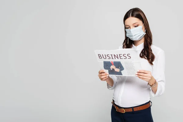 Jovem empresária grávida em máscara médica com jornal de negócios isolado em cinza — Fotografia de Stock