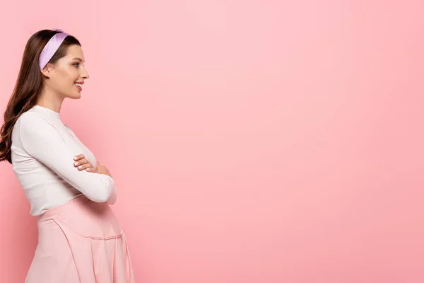 Vista lateral da jovem feliz bonita mulher grávida tocando barriga isolada em rosa — Fotografia de Stock