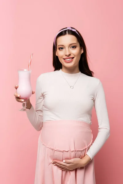 Heureux jeune jolie femme enceinte avec milkshake isolé sur rose — Photo de stock