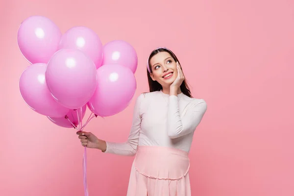 Щаслива молода красива вагітна жінка з повітряними кулями ізольована на рожевому — стокове фото