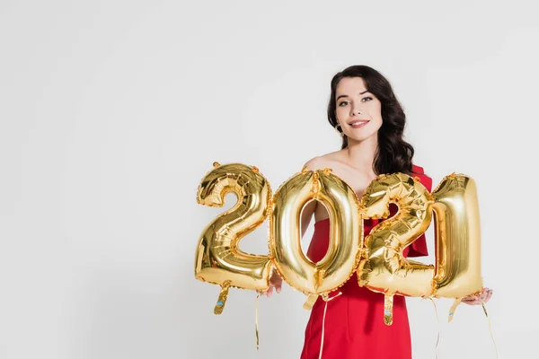 Mulher sorridente segurando balões dourados em forma de 2021 números isolados em cinza — Fotografia de Stock