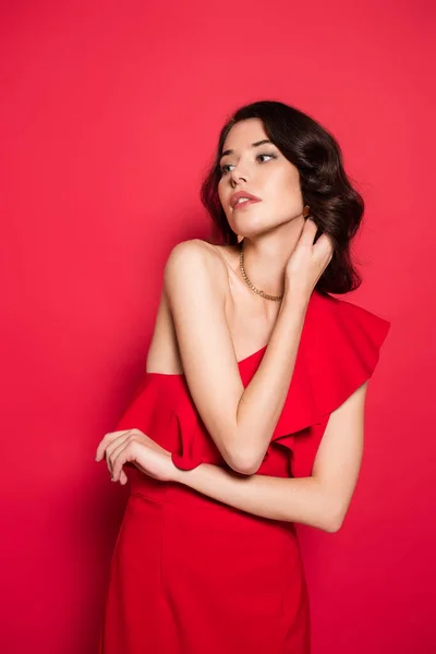 Brunette femme en robe rouge regardant loin sur fond rouge — Photo de stock