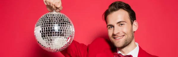 Uomo allegro che tiene la palla da discoteca su sfondo rosso, banner — Foto stock