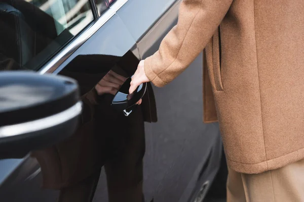 Cropped view of woman opening door of black car — Stock Photo