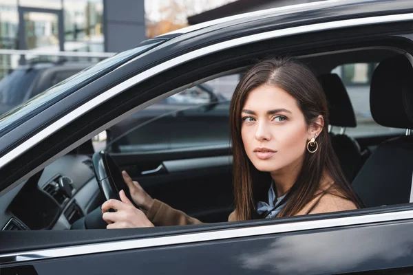 Giovane donna che guarda fuori dal finestrino laterale durante la guida di auto — Foto stock