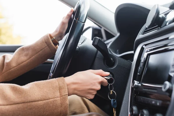 Visão parcial da mulher que inicia o carro enquanto segura o volante — Fotografia de Stock