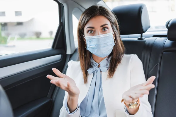 Verwirrte Frau zeigt Achselzucken und blickt in Kamera, während sie im Auto sitzt — Stockfoto