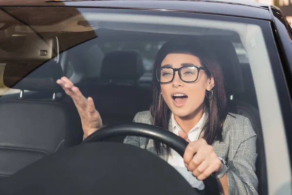 Mulher zangada gritando e gesticulando enquanto dirigindo carro em primeiro plano turvo — Fotografia de Stock
