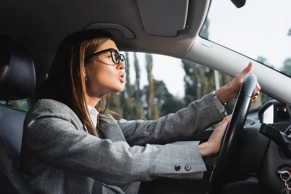 Femme d'affaires mécontente regardant vers l'avenir et bip tout en conduisant voiture — Photo de stock