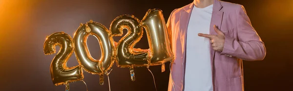 Ausgeschnittene Ansicht eines Mannes, der mit dem Finger auf schwarze Luftballons zeigt, Banner — Stockfoto