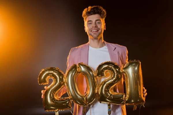 Homem alegre segurando 2021 números balões em preto — Fotografia de Stock