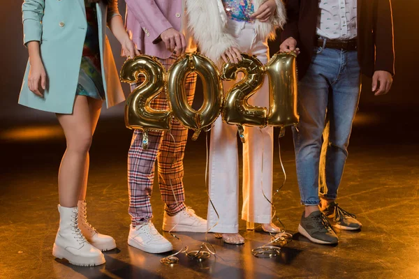 Cropped view of friends holding 2021 numbers balloons on black — Stock Photo