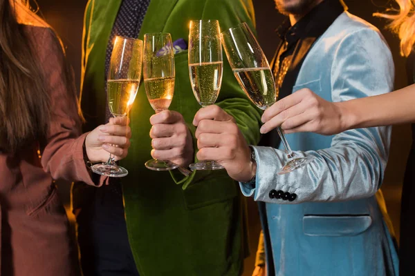 Vista ritagliata di amici brindare bicchieri di champagne su nero — Foto stock