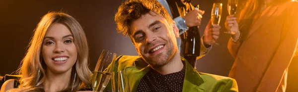 Happy couple toasting glasses with champagne and smiling on black, banner — Stock Photo