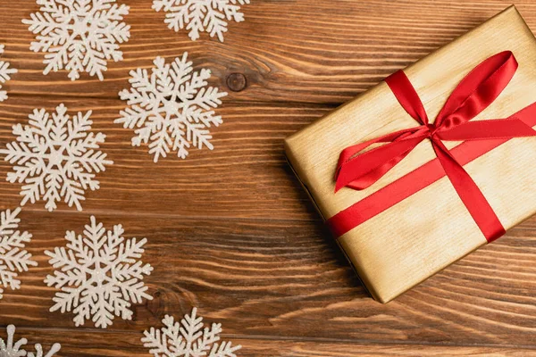 Top view of winter snowflakes and present on wooden background — Stock Photo