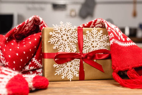 Winter knitted red scarf and mittens and present on wooden table — Stock Photo