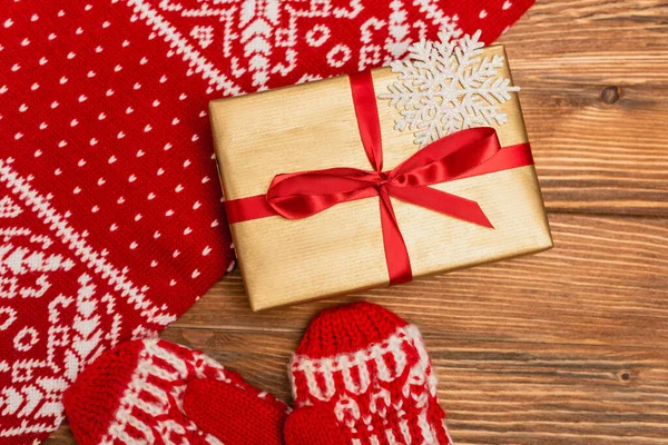 Top view of gift box and red knitted scarf and mittens on wooden background — Stock Photo