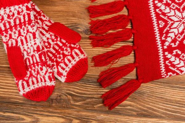 Top view of red knitted scarf and mittens on wooden background — Stock Photo