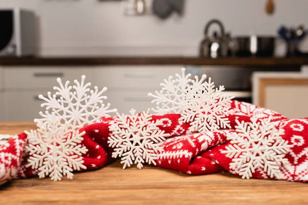 Winter-Schneeflocken und gestrickter roter Schal auf Holztisch — Stockfoto