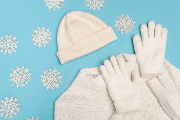 Top view of winter white knitwear and snowflakes on blue background — Stock Photo