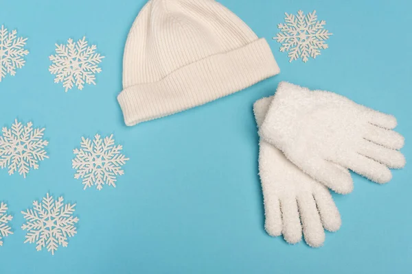 Top view of winter white knitwear and snowflakes on blue background — Stock Photo