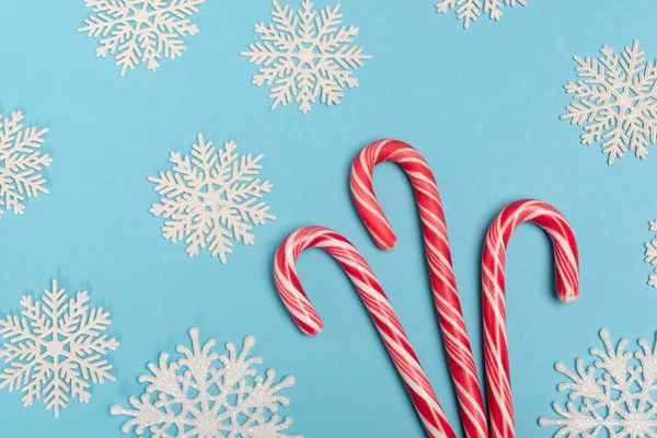 Top view of candy cane and snowflakes on blue background — Stock Photo