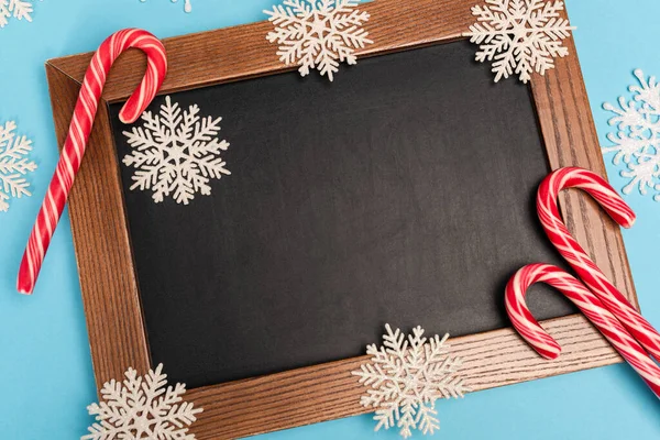 Top view of chalkboard, candy canes and snowflakes on blue background — Stock Photo