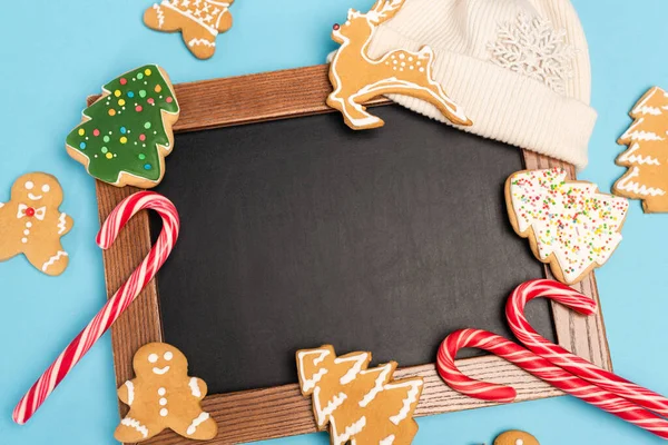 Top view of gingerbread cookies and chalkboard on blue background — Stock Photo