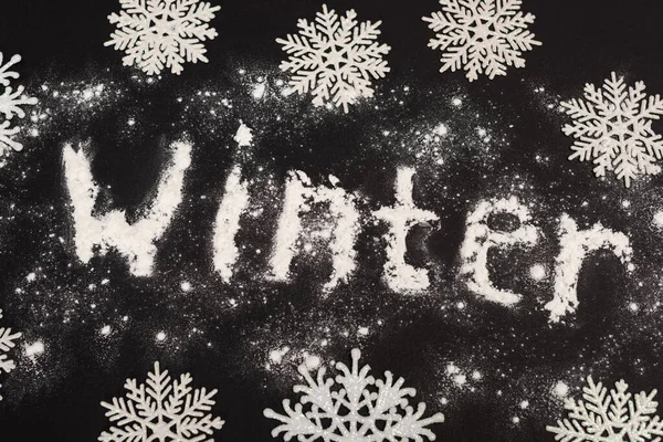 Top view of word winter and snowflakes on black background — Stock Photo