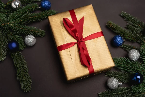 Draufsicht auf geschmückten Weihnachtsbaum und Geschenk auf schwarzem Hintergrund — Stockfoto