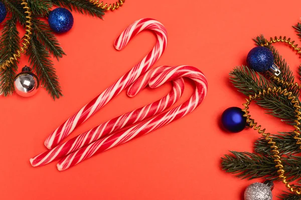 Vista superior del árbol de Navidad decorado y bastones de caramelo sobre fondo rojo - foto de stock