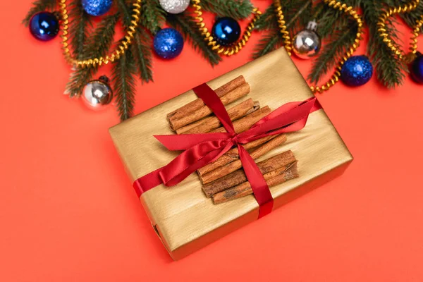 Vue de dessus de sapin de Noël décoré, cadeau avec cannelle sur fond rouge — Photo de stock