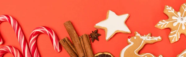 Vue du dessus des cannes à bonbons, des épices et des biscuits au pain d'épice sur fond rouge, bannière — Photo de stock